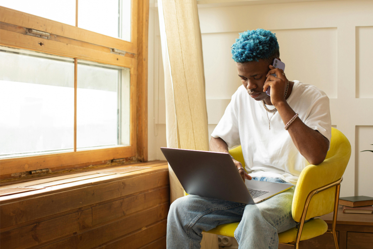 Man using his phone while look at a laptop