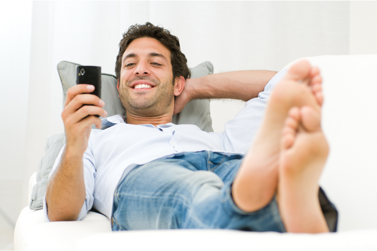 Man reclining and texting on his phone as he smiles