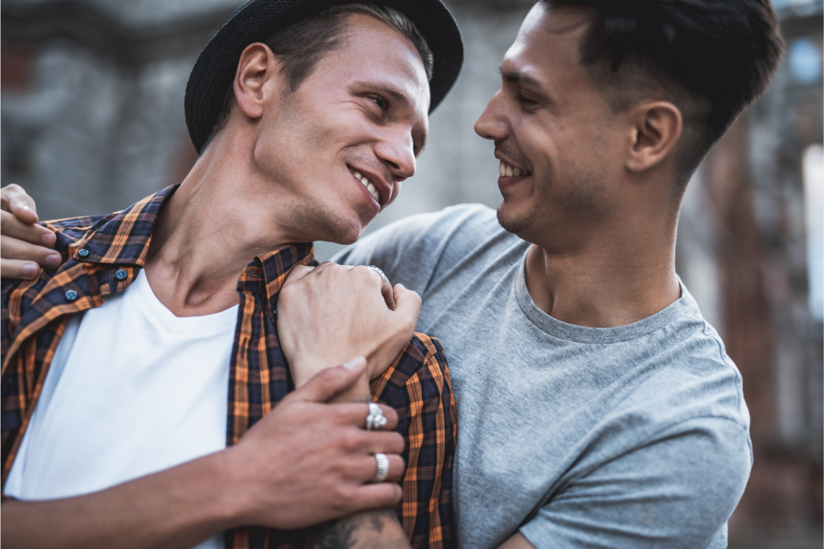 Cheery gay men holding each other 