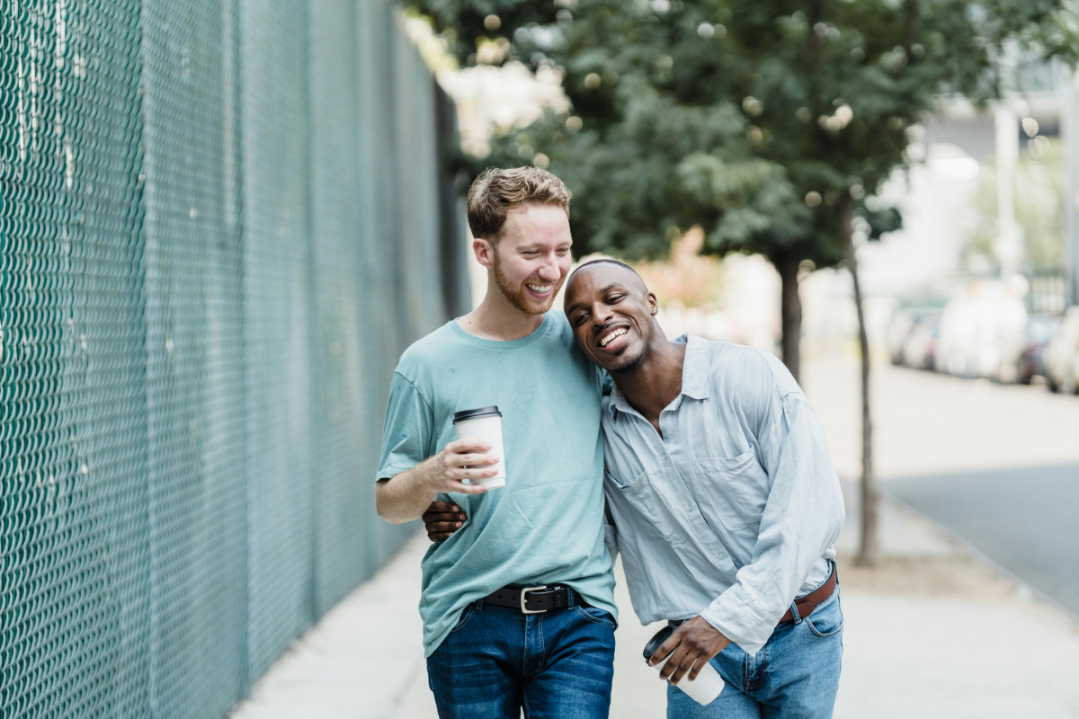 Happy gay men couple walking along the street 